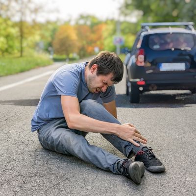 Hit And Run Concept. Injured Man On Road In Front Of A Car.